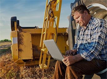 farmer sitting on a large tire checking energy use